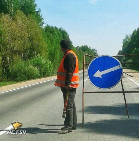 Суровый дорожный рабочий регулирует движение на ремонтном участке трассы Новосибирск - Томск при помощи бейсбольной биты.