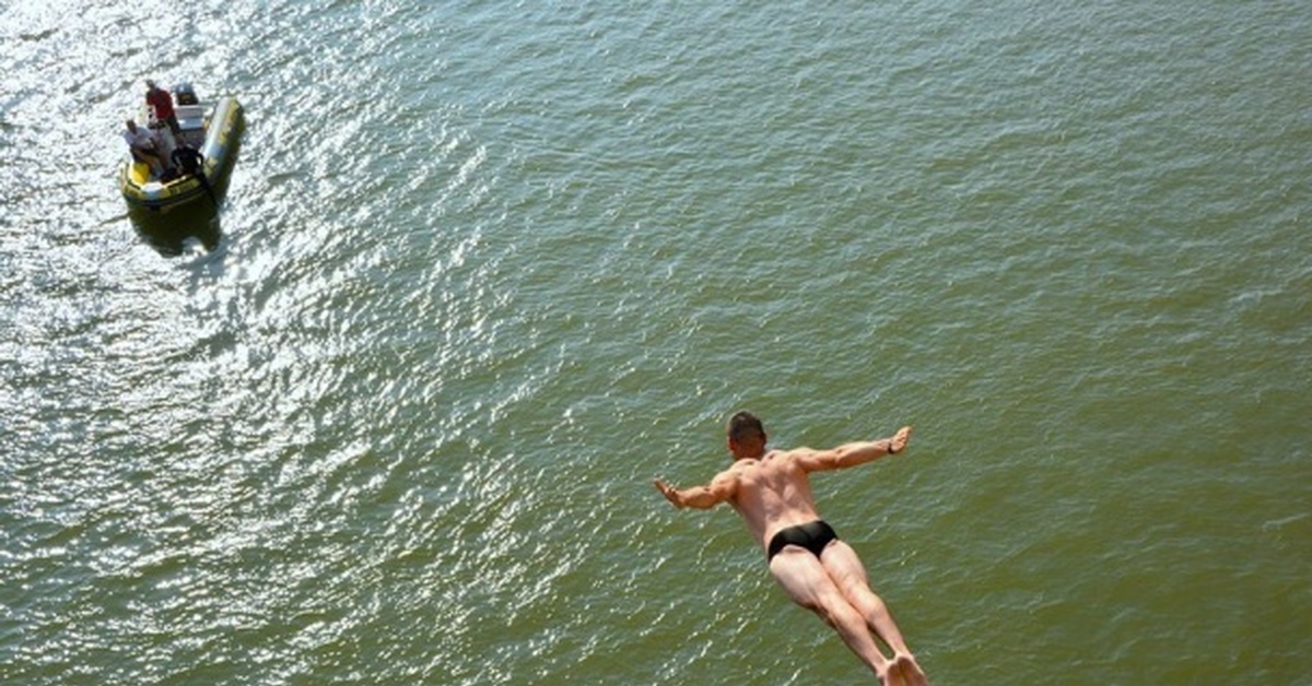 Экстремалов погибших. Прыжки в воду с моста. Мостик для ныряния. Парень прыгает в воду.