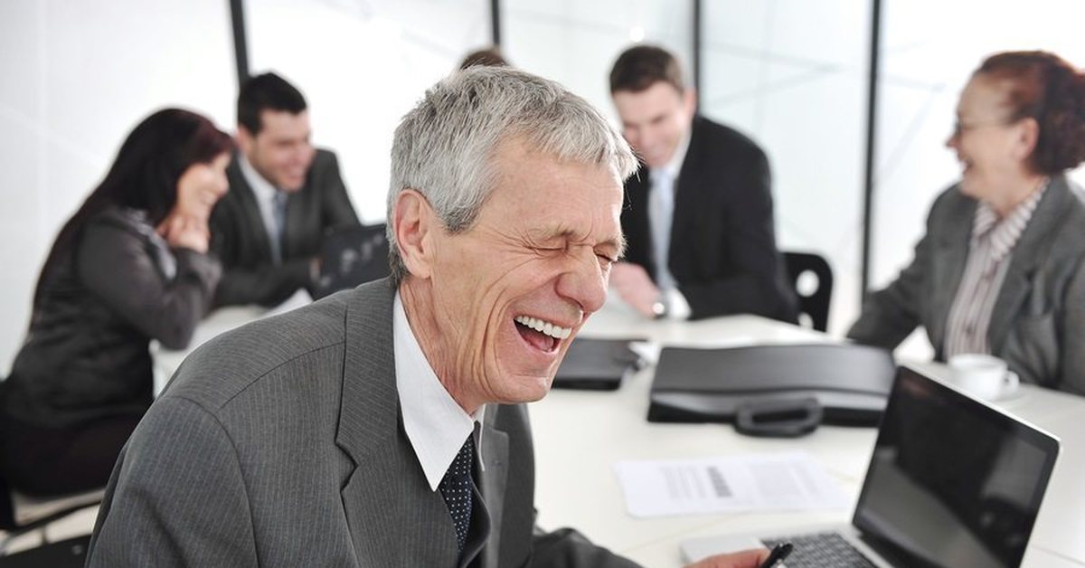 Коллега шутит. Люди смеются в офисе. Начальник смеется. Предприниматель смеется. Смеющийся начальник в офисе.